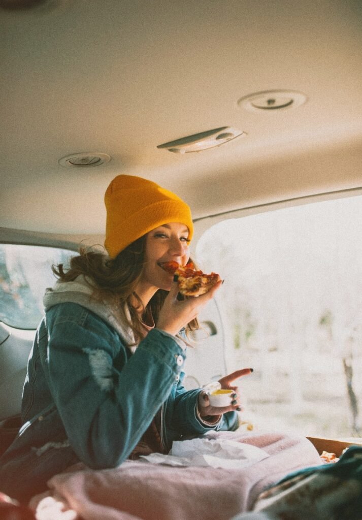 woman eating pizza inside vehicle, Yolculuk Atıştırmalıkları